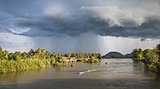 Landscape with stormy clouds and a pirogue on the Mekong at golden hour, from the bridge between Don Det and Don Khon.