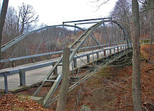 Bridge seen from side with some tree trunks in front, and side structure visible