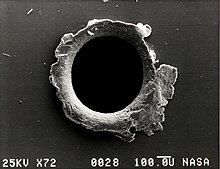 Electron micrograph image of an orbital debris hole made in the panel of the Solar Max satellite SMM panel hole.jpg