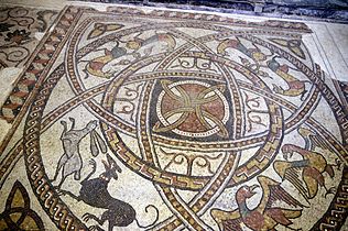 Mosaïque romane dans le chœur de l'église. Un chien poursuivant un lièvre, deux aigles, deux paires de félins les queues entrelacées et au centre une rosace géométrique.