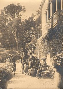 Paul Bourget au Plantier de Costebelle avec Henry Bordeaux et quelques amis, photo d'extérieur, certains sont assis sur un banc.