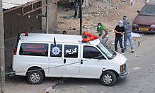 Palestinians in Qalandiya throw rocks from behind an ambulance during a riot as part of the Nakba protests. Flickr - Israel Defense Forces - Qalandiya Rioters Use Ambulance for Cover While Hurling Rocks.jpg