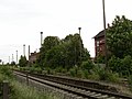 Empfangsgebäude mit anschließendem Güterschuppen, Pflasterung der Zufahrt sowie Stellwerk B1 am Bahnübergang