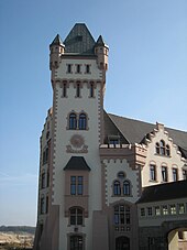 Turm der Hörder Burg. In der Turmmitte eine Sonnenuhr, rechts Übergang zu weiteren Anbauten.