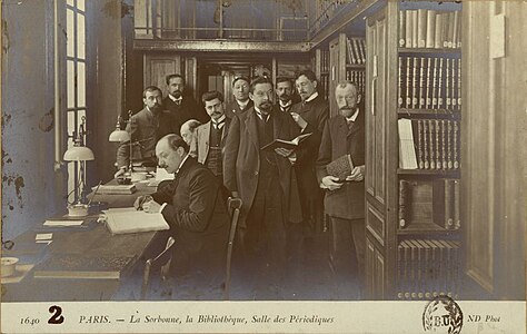 La salle des périodiques de la bibliothèque de la Sorbonne en 1905, de gauche à droite Ch. Beaulieux, Macaigne, Victor Mortet, Philibert de Clermont, M. Lévy, Bultingaire, F. Chambon, Borel et deux lecteurs assis à la table, Lucas de Peslouan et U. V. Chatelain (au fond).