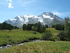 Le hameau du Monal à Sainte-Foy-Tarentaise en Haute-Tarentaise, dans le parc de la Vanoise, en Savoie. En arrière plan, se dresse les faces est du Mont Turia sur la droite du massif et du Mont Pourri au centre (avec la Brèche Puiseux à son pied, côté sud), ainsi que le Dôme de la Sache sur la gauche. Au premier plan, coule paisiblement le ruisseau du Clou.