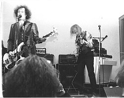 A black and white photo, with two band members playing.