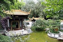 Chinesische Pagode mit geschwungenem Dach auf einer Steinplattform, die flach über ein Wasserbecken ragt