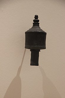 Instrument de mesure en métal présenté sur un mur, ayant été fiché sur un poteau en bois