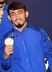 Balabəy Ağayev in blauer Trainingsjacke präsentiert eine Medaille.