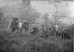 Sekelompok Suku Dayak bersenjata sibuk memburu kepala musuh (Ngayau) di lingkungan Tumbang Anoi, Kalimantan Tengah. (Mungkin sebelum Bulan Juli 1894)