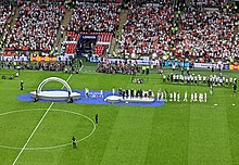 England captain Leah Williamson stands at the back of her team to be presented with the 2022 Women's Euro trophy by William, Duke of Cambridge; Williamson, the incumbent permanent women's captain, is the only captain to lead England to a Euro victory and the only captain to lead the women's team to an international title. Euro 2022 Final England v Germany (52254784564) (cropped).jpg