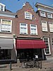 Huis met in- en uitgezwenkte topgevel, winkel