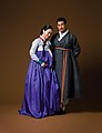Hanbok (costume traditionnel): Une femme portant un jeogori (veste) serré et une chima (en) (jupe) / Un homme en durumagi (manteau traditionnel)