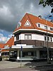 Blok met winkels met brede luifel en daarboven woningen, bouwstijl Amsterdamse School, onderdeel van het centrale achthoekige plein van Tuindorp Nieuwendam