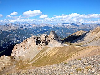 Blick auf größere Teile des Queyras von der Pointe de Rasis (2844 m), Blick nach Nordwesten: Combe du Queyras (links im Mittelgrund, teilweise im Schatten), Col d’Izoard (rechts der Bildmitte, im Hintergrund), Pic de Rochebrune (höchster Gipfel rechts, im Hintergrund).