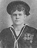 Head and shoulders of a young white man with thick hair wearing a flat cap and a sailor suit with three medals on the left breast.