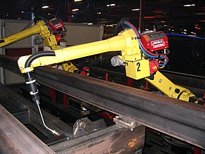A six-axis articulated welding robot reaching into a fixture to weld FANUC welding robot reaching.jpg