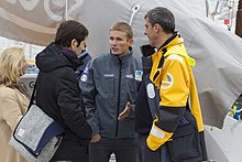 Le skipper Fabien Delahaye en discussion avec deux autres personnes devant son monocoque