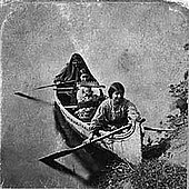 Three or four dark haired women near the shore in a canoe