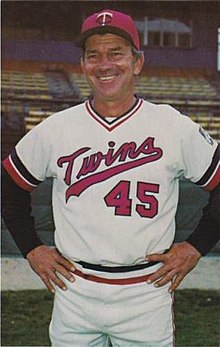 A man in a white baseball uniform and red cap