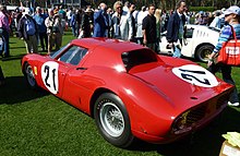 Вид сзади красного спортивного автомобиля Ferrari, стоящего на траве на автомобильном шоу