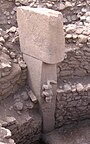 Predador de larga cola (¿un cocodrilo?), gravado en altorrelieve en el mismo bloque de roca que lo soporta.