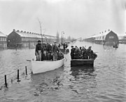 Bewoners van het overstroomde Tuindorp Oostzaan worden met roeiboten geëvacueerd; 14 januari 1960.