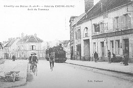 La route de Paris avec la façade de l'auberge à droite, photographiée pour une carte postale au tournant du XXe siècle.