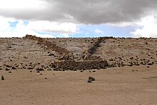 Vestige d'un chaccu. Des murs en pierres forment un entonnoir qui se termine en enclos.