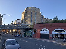 Street and assign underneath railway viaduct. On the right of the image, The rail bridge over the street transitions to an elevated Brick viaduct with arches