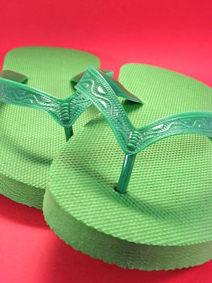 green plastic flip flops against colored backg...