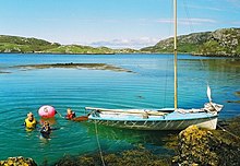 Небольшая синяя шлюпка находится в аквамариновом водоеме рядом со скалистым берегом под голубым небом. Трое человек плывут с кормы лодки рядом с красным буем.