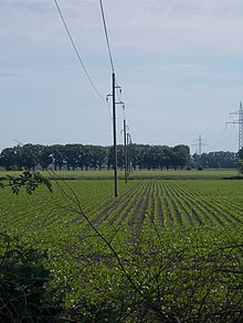 Wooden electricity poles in Germany. In central Europe, lines usually run just straight across fields, rows of poles accompanying roads are quite rare. Hv braunschweig20.jpg