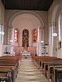 Průhled kostelem do presbytáře. Na oltářem je nástěnný obraz, po stranách dvě z celkem čtyř vitrážových oken