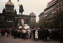 Before the June 1990 elections, demonstrators on Wenceslas Square in April gather under a poster where the red star and initials of the KSC has a swastika painted on top of it while the coat of arms depicted is from before the formation of the Czechoslovak Socialist Republic Prague Demonstration April 1990.jpg