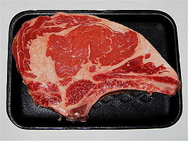 A rib steak, raw, with bone attached