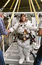 Wearing an extravehicular mobility unit (EMU) spacesuit, Dunbar prepares to don a helmet and be lowered by a hoist device for a session of underwater training in the Johnson Space Center's weightless environment training facility (WET-F). S89-41597 orig.jpg