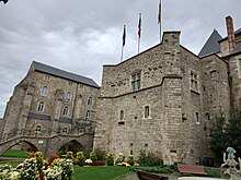 Vue de deux édifices anciens, une grosse tour carrée à droite et un autre bâtiment sur la gauche, les deux édifices étant séparés par un pont