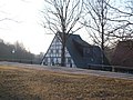 Wohnstallhaus, drei Seitengebäude und Handschwengelpumpe eines Mühlenanwesens, mit Hausbäumen (Obstmühle)