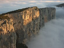 Photographie montrant une falaise vue du haut entourée de nuages