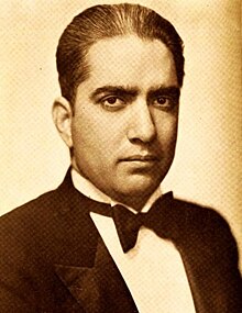Sepia portrait photograph of the actor wearing a smart suit and bowtie