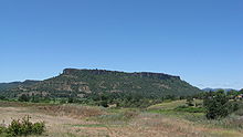 Lower Table Rock from across a field. Similar to Upper Table Rock, it rises steeply to its very flat top.