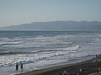 Two people on the shore of the Pacific Ocean