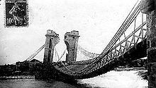Un pont suspendu dont le tablier s'effondre ; la pile visible est à moitié détruite.