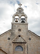 Ulaz u crkvu, natpis nad ulaznim vratima i tri zvona na preslicu