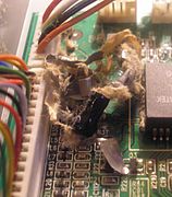 Catastrophic failure of a capacitor has scattered fragments of paper and metallic foil