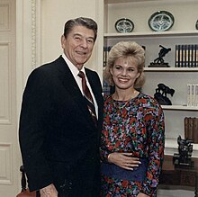 Color portrait of Reagan and Carlson looking at the camera and smiling before an Oval Office wall