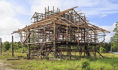 Seorang tukang kayu sedang mengerjakan bingkai rumah tradisional yang baru dibangun di Kampung Salarom, Sapulut, Sabah, Malaysia.