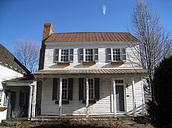 A two-story white wooden structure with a front porch on the first story